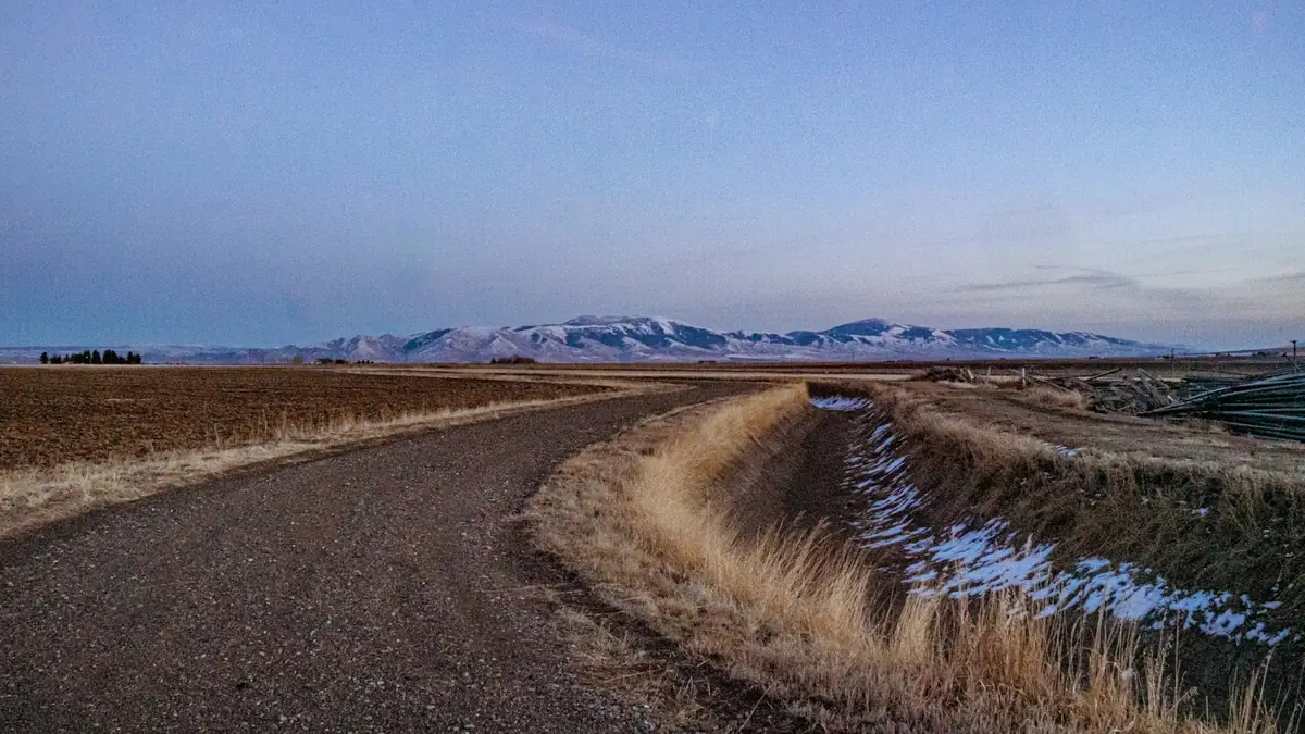 A gravel road beside an irrigation ditch running through farmland - Leak Detection in Caldwell